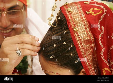 Indian Gujarati Bridegroom putting red powder called Sindoor on brides