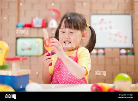 toddler girl pretend play food preparing role against cardboard blocks ...