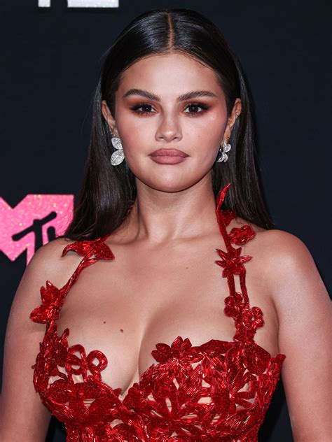 Selena Gomez almost slips out of plunging button-down shirt as she