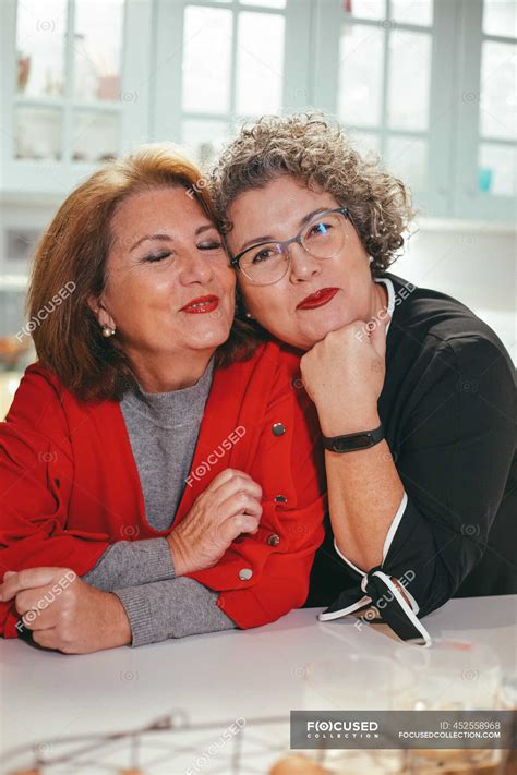 Glad middle aged lesbian woman leaning on shoulder of smiling female
