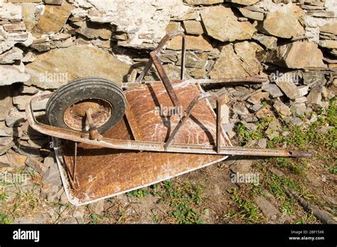 a rusty wheelbarrow overturned and abandoned in a farm Stock Photo - Alamy