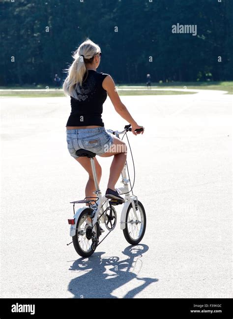 Rear view of a woman riding bicycle in the park, Lithuania Stock Photo ...