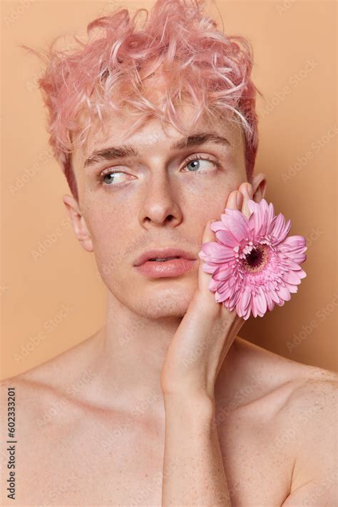 vertical image  thoughtful pink haired man holds gerbera flower
