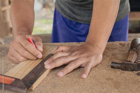 craftsman using the pencil marking make on the wooden product working ...