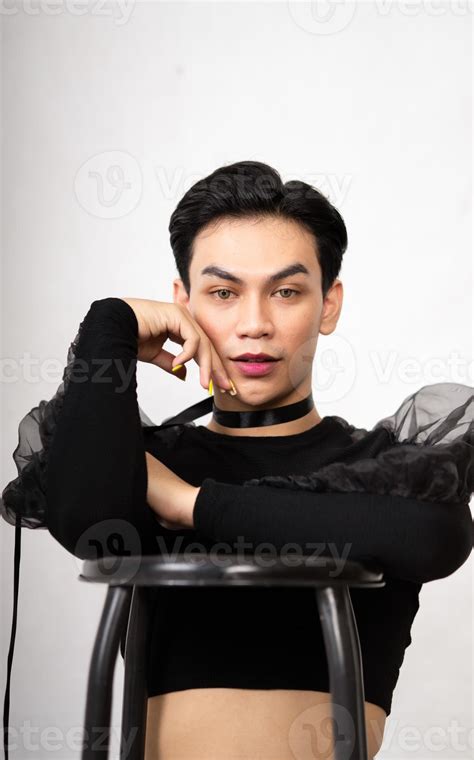 beautiful Asian man posing with the chair while wearing a black costume