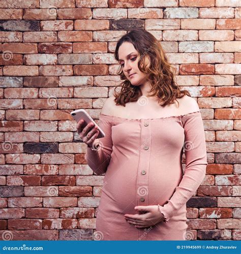 Portrait of a Pregnant Woman in a Red Tight-fitting Belly Dress with a