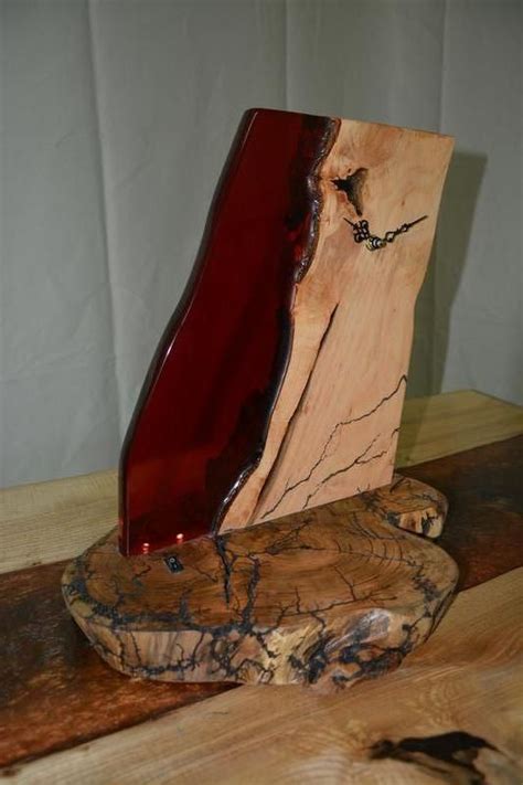 a red vase sitting on top of a wooden table next to a piece of wood