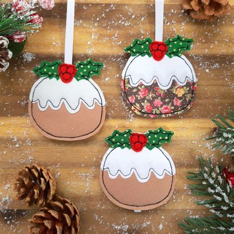 three decorated christmas puddings hanging from hooks on a wooden table ...