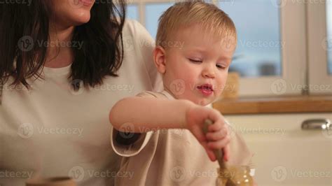 Happy family at home. Mother feeding baby in kitchen. Little boy with