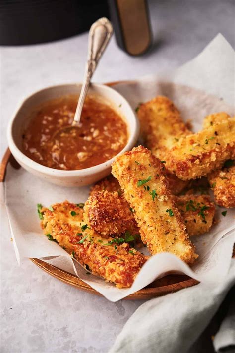 Air fried mozzarella sticks on a serving plate with sweet chili sauce