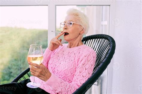 Old fashioned senior stylish woman sitting on terrace smoking cigarette