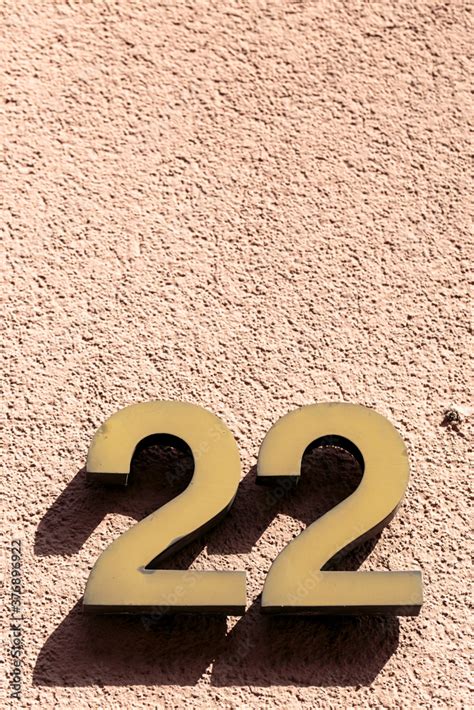 Number 22 twenty-two golden metal address sign fixed onto textured