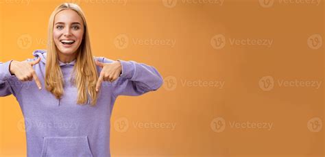 Amused joyful nice blond girlfriend pointing down present cool new