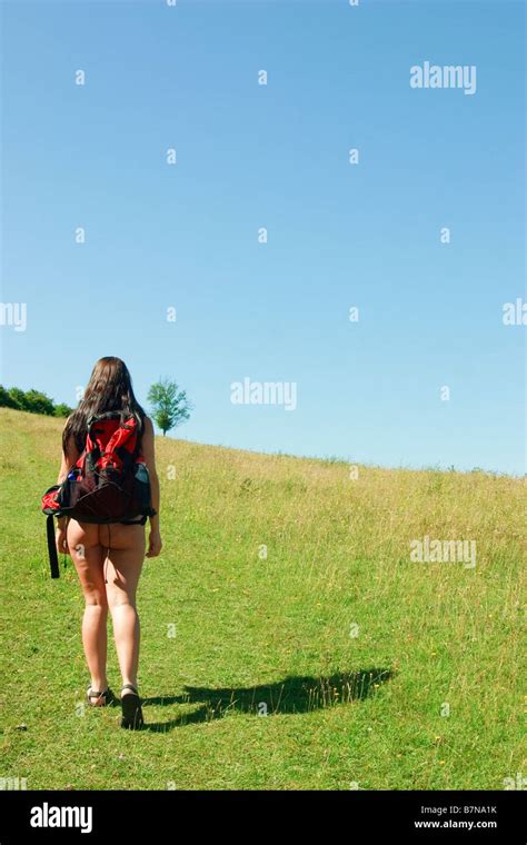 Rear view of naked female naturist rambler enjoying the British