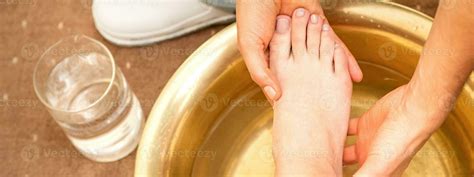 Washing female foot in a special container by male masseur in spa salon ...