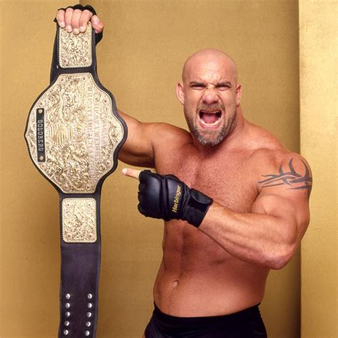 a man holding a wrestling belt in his right hand and pointing at the ...
