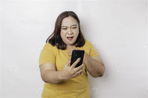 The angry and mad face of big sized Asian woman in yellow shirt while