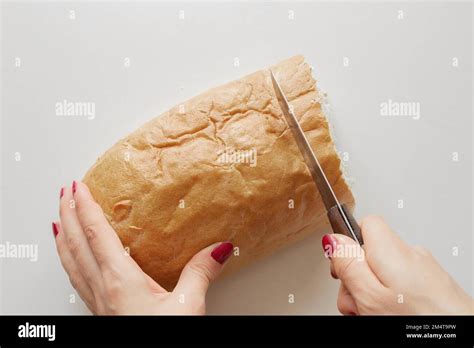 female hand cuts  piece  bread   knife   white table