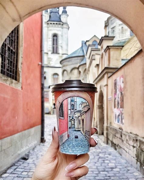 a person holding up a cup in the middle of a cobblestone alleyway