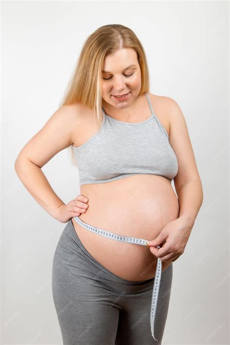 Premium Photo | A pregnant girl measures her stomach with a tapeline