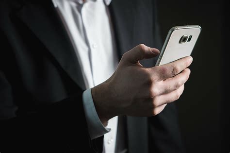 person black formal coat holding samsung galaxy android smarpthone