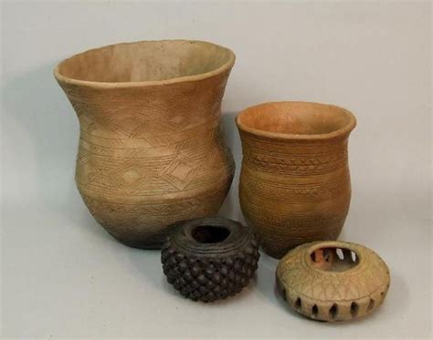 three vases and one bowl are sitting on the table together, some with ...