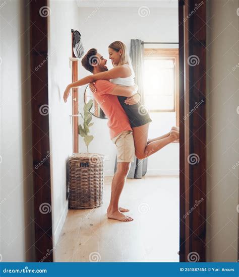 Happy Young Boyfriend Holding Girlfriend in Arms As he Lifts Her Up