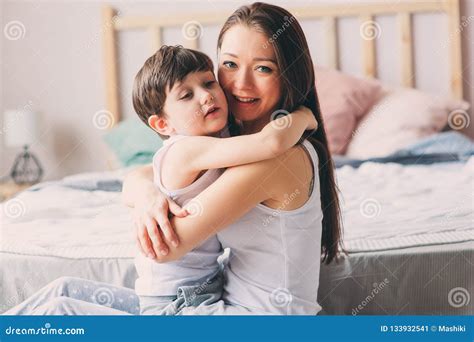 Happy Loving Mother Hugs with Child Son in the Morning in Bed Stock