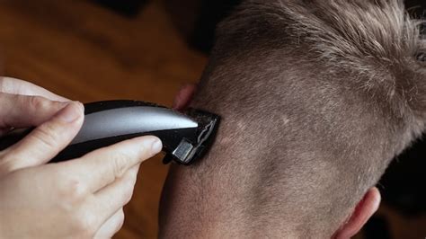 kapper knippen haar op de achterkant van een hoofd met een trimmer