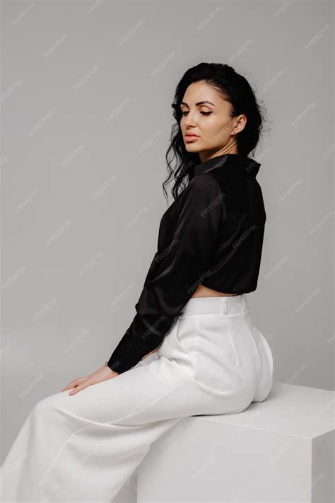 premium photo  woman   black top  white pants sits   white